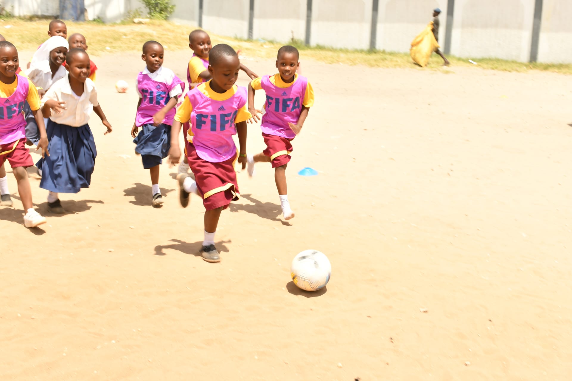 Children chasing a football with pure joy on a sunlit field