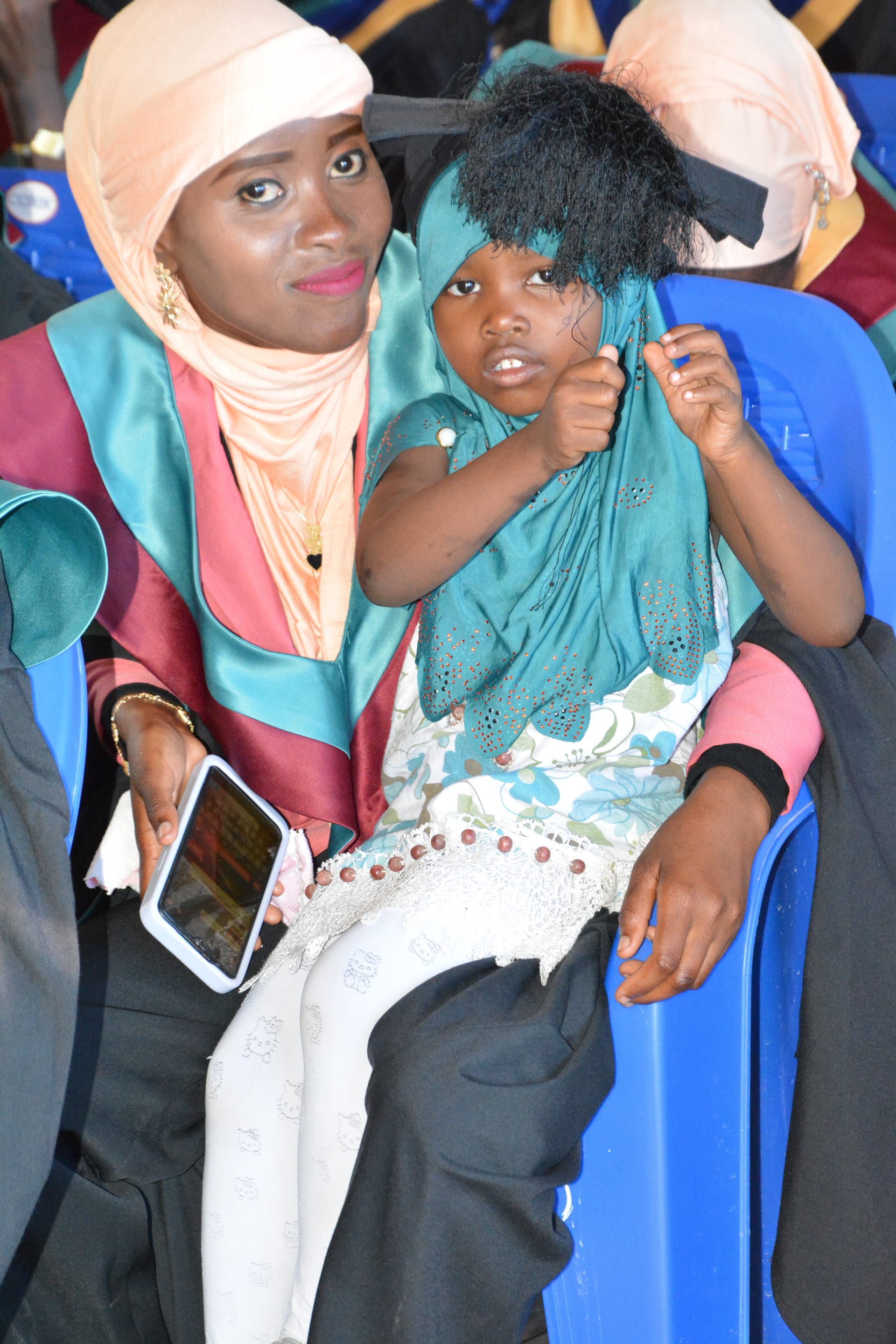 A young mother in her graduation gown with her daughter, the most powerful image of intergenerational impact